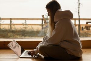 A person working remotely on a laptop by a lake, enjoying a tranquil outdoor environment.