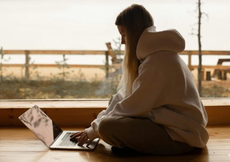 A person working remotely on a laptop by a lake, enjoying a tranquil outdoor environment.